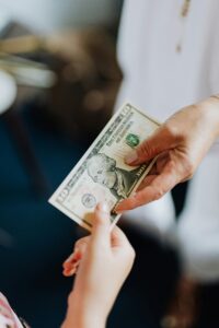 Close-up of hands exchanging a US dollar bill, emphasizing financial transactions.