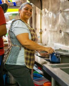 Hispanic woman smiling while cooking in Ciudad de México kitchen, showcasing culinary skills.