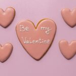 Top view of sweet heart shaped cookies saying Be My Valentine on pink background